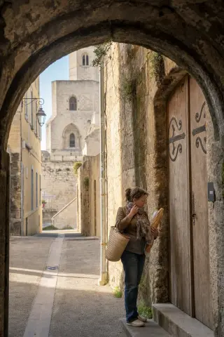 A woman pausing in a quiet stone alleyway near the abbaye Saint-Victor, with afternoon light on ancient walls and a subtle, authentic Marseille atmosphere.