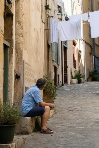 Authentic Marseille alleyway with resident reading a plaque on a weathered doorstep under soft Mediterranean light